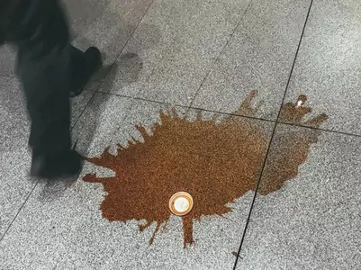 Une personne marchant sur un sol carrelé avec une tache de café.