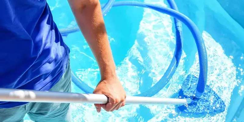 Travailleur utilisant un écumeur de piscine pour l'entretien, mettant en avant le service de nettoyage de piscine.