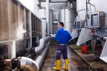 Un homme en salopette bleue lavant une grande machine industrielle à Ait Melloul, illustrant les services de nettoyage dans la région.
