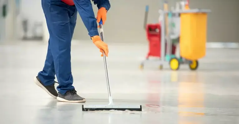 Une personne s'applique diligemment à nettoyer le sol, assurant ainsi la propreté et l’ordre, dans le cadre du service de nettoyage du sol.